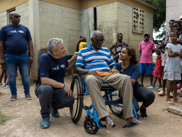 A man in a wheelchair surrounded by people after receiving a wheelchair donation from Free Wheelchair Mission in the Dominican Republic.