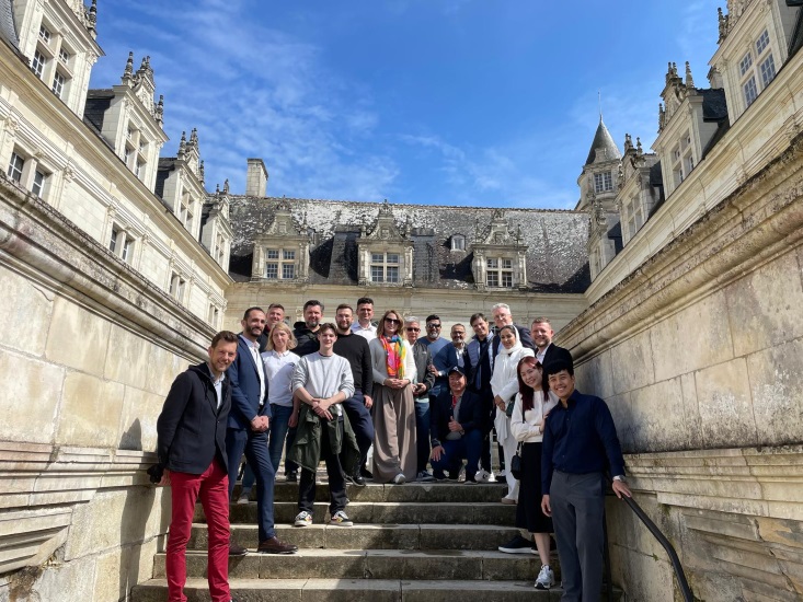 Group of smiling people posing in front of a castle