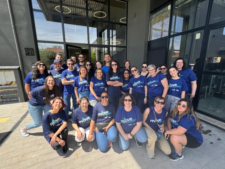 Group photo with people in blue T-shirts in front of a building.