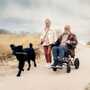 Alber Erivo power wheelchair user walking dog