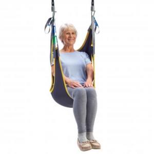 Person seated in a full‑body patient sling suspended from overhead lift straps.